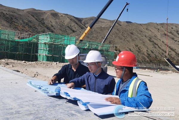 侯爭光(左二)在工程現(xiàn)場查看圖紙